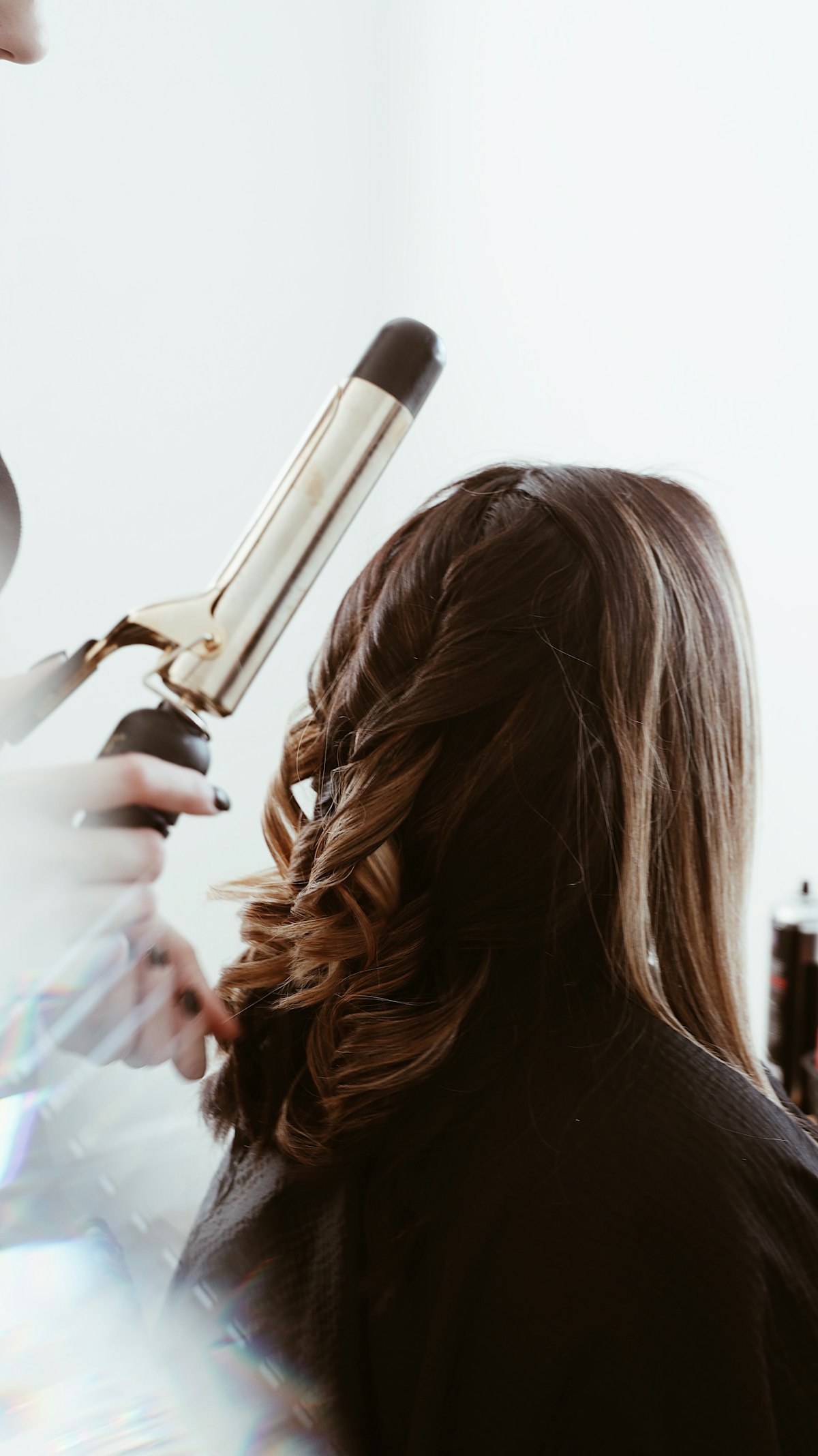 Estilista rizando el cabello de una clienta