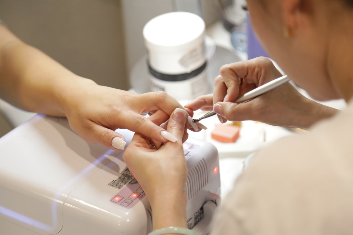 Manicurista trabajando en las uñas de una clienta