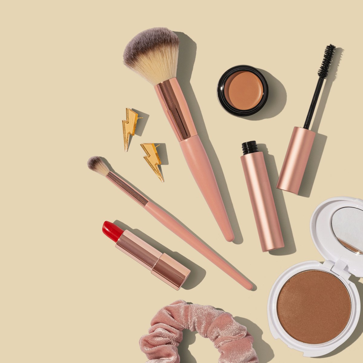 Brochas y productos de maquillaje sobre fondo crema